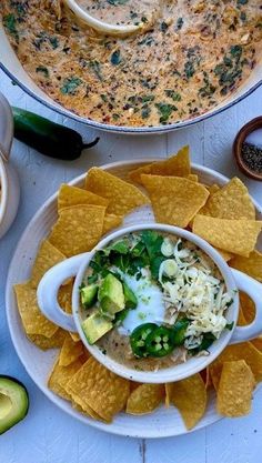 a bowl of soup with tortilla chips and avocado on the side