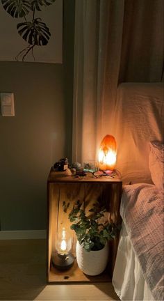 a night stand with two candles on it next to a bed in a small room