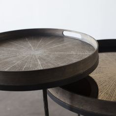 two round trays sitting next to each other on top of a wooden table with metal legs