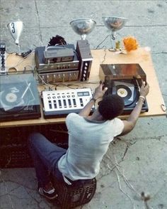 a person sitting at a table with an electronic device and record player on it's side