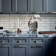 a kitchen with gray cabinets and marble counter tops, gold pulls on the handles to match the cabinetry