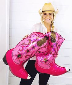 a woman in cowboy hat holding pink boots