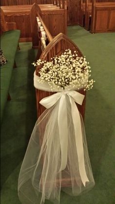 a bouquet of baby's breath sits on the pews of a church during a wedding ceremony