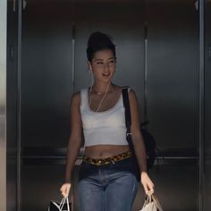 a woman with headphones is walking through an elevator carrying shopping bags and listening to music