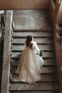 a woman in a wedding dress walking down some stairs