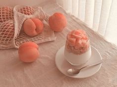 there are peaches on the table next to an empty cup and saucer with spoons