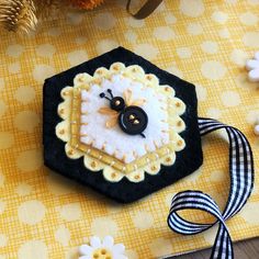 a black and white brooch sitting on top of a table next to some flowers