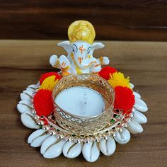 a small ganeshi idol sitting on top of a wooden table next to a candle holder