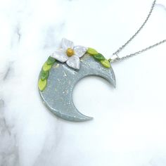 This exquisite necklace is the perfect blend of celestial magic and cottagecore charm. The crescent moon pendant is handcrafted from polymer clay and features a delicate botanical design, complete with a charming flower and leaves. The pendant is hung on a delicate 18-inch chain, making it the perfect length to layer with other necklaces or wear on its own.Whether you're a celestial witch, a cottagecore enthusiast, or a pastel goth goddess, this necklace is sure to turn heads and make you feel l Goth Goddess, Celestial Witch, Clay Moon, Celestial Magic, Flower And Leaves, Chain Making, Crescent Moon Pendant, Cup Art, Botanical Design