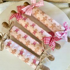 four wrapped candy sticks with gingerbreads and bows on them sitting on a plate