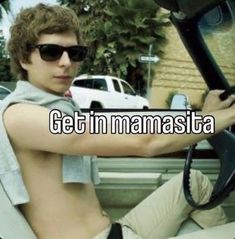 a shirtless young man sitting in the driver's seat of a car with his hand on the steering wheel