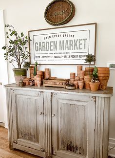 an old cabinet with potted plants on top and a garden market sign above it