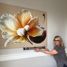 a woman standing in front of a large flower on a wall mounted to the side of a fireplace