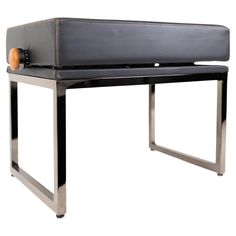 a black leather bench with an orange button on the back and metal legs, against a white background