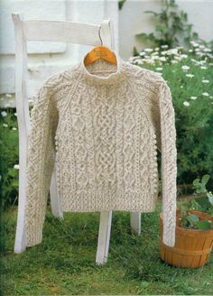 an old sweater hanging on a chair in the grass next to a potted plant