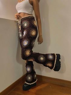 a woman standing on top of a wooden floor wearing crocheted pants and boots