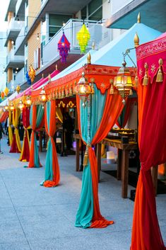 many different colored drapes are lined up on the side of the street with lights