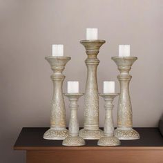 four white candles sitting on top of a wooden table