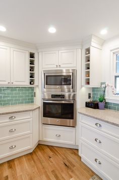 a kitchen with white cabinets and stainless steel oven in the center, along with wooden flooring