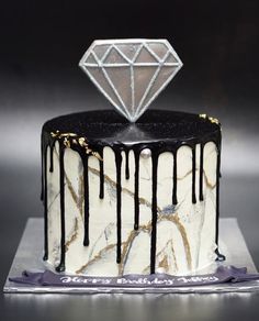 a white cake with black icing and a diamond on top