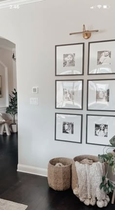 a living room with pictures on the wall and two baskets in front of it,