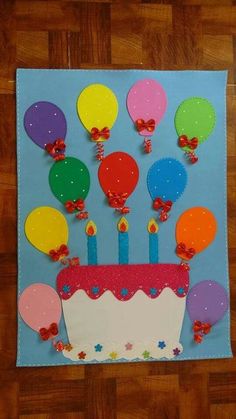 a birthday cake with candles and balloons on the top is made out of colored paper