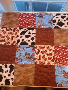 a quilted table cloth with horses and cowboys on it in front of a window