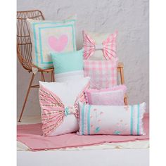 pillows with bows and hearts on them are sitting on a pink blanket next to a chair