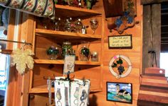 a wooden shelf filled with lots of glassware and vases on top of it