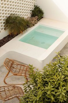 a small pool in the middle of a patio with chairs and potted plants next to it