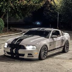 a white mustang parked in a parking lot at night