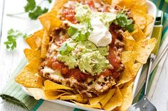 nachos on a plate with sour cream and salsa