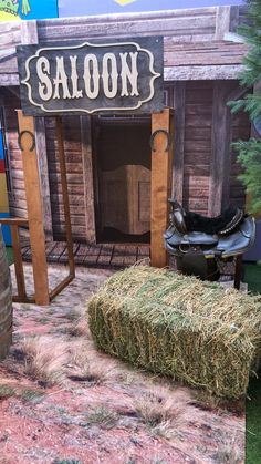 a horse saddle sitting on top of a pile of hay next to a sign that says saloon