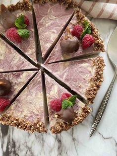 a pie with raspberries and chocolates on it sitting on a marble table