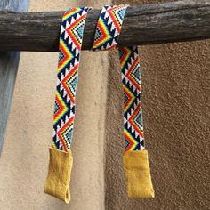 a pair of yellow boots hanging from a wooden pole next to a tan colored wall