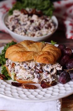 a chicken salad sandwich on a croissant with grapes and pecans