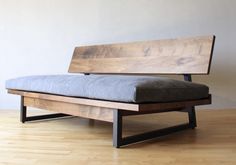 a bed that is sitting on top of a wooden floor next to a white wall