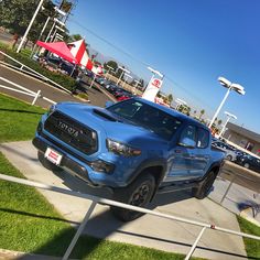 a blue toyota truck parked in front of a gas station with other cars behind it