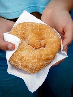 a person holding a doughnut on top of a white paper towel in their hands