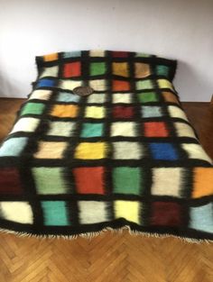 a multicolored blanket sitting on top of a wooden floor