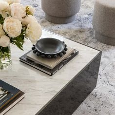 a vase with white flowers sitting on top of a table next to books and magazines