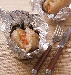 two hot dogs wrapped in aluminum foil with forks