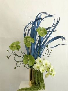 a vase filled with white flowers and green leaves