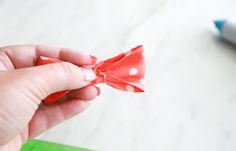 a person holding a red bow with white polka dots on it, near a marker