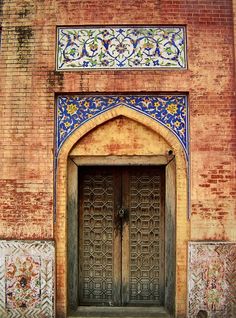 an old building with two wooden doors and ornate designs on the front door is shown