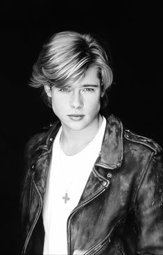 a young man with blonde hair wearing a black leather jacket and white t - shirt