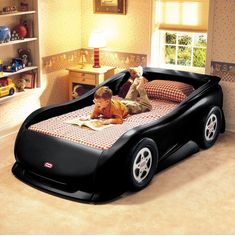 a young boy laying on top of a bed in a bedroom next to a book shelf