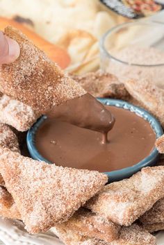 someone dipping chocolate into some food on a plate