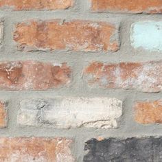 an old brick wall with some paint chipping off the top and bottom part,