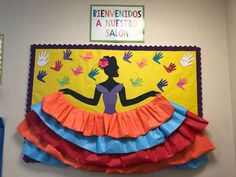 a bulletin board with hand prints on it and a woman in a colorful frilly skirt